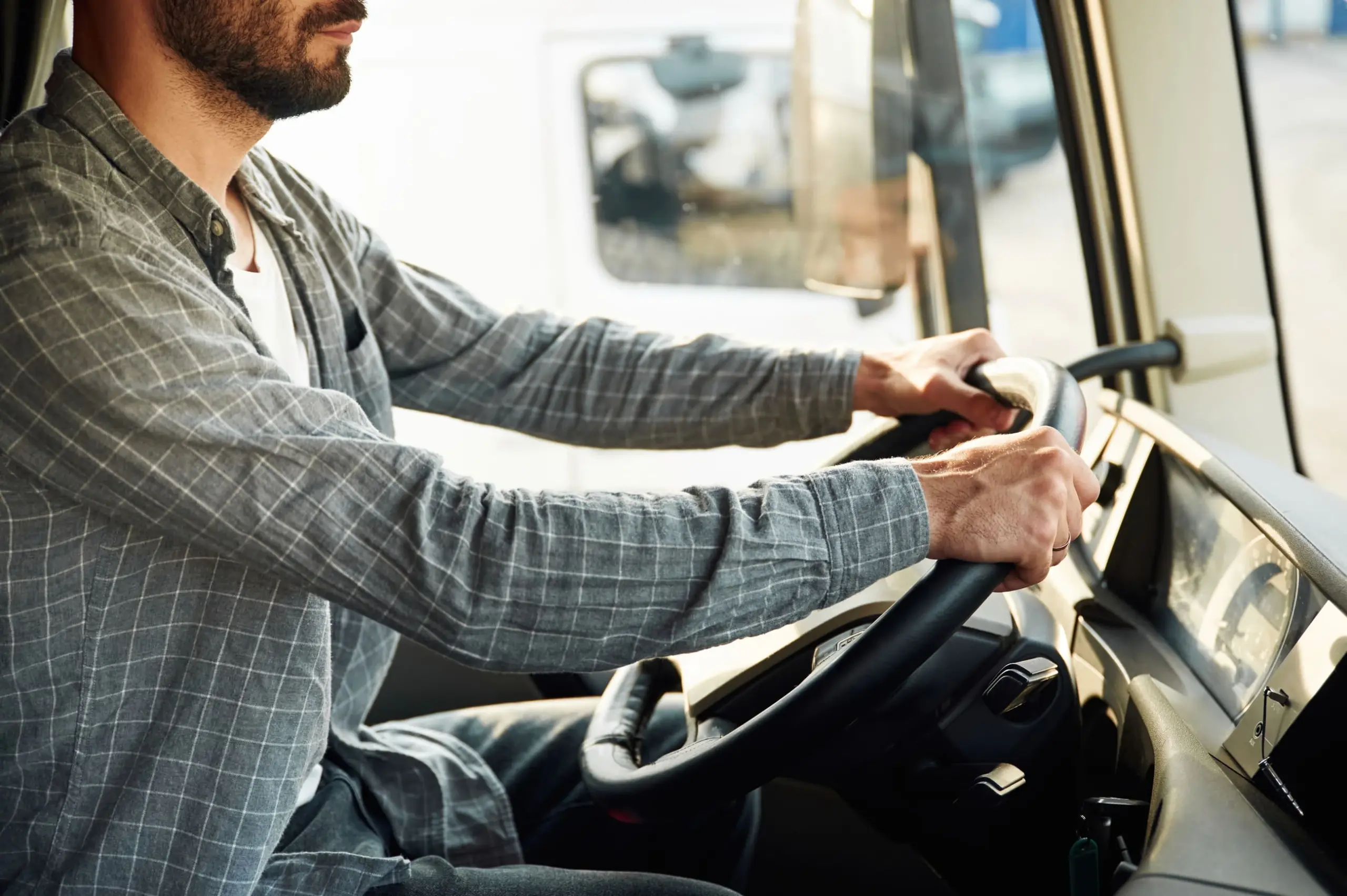 Un homme en chemise en train de conduire un camion, vu du côté passager