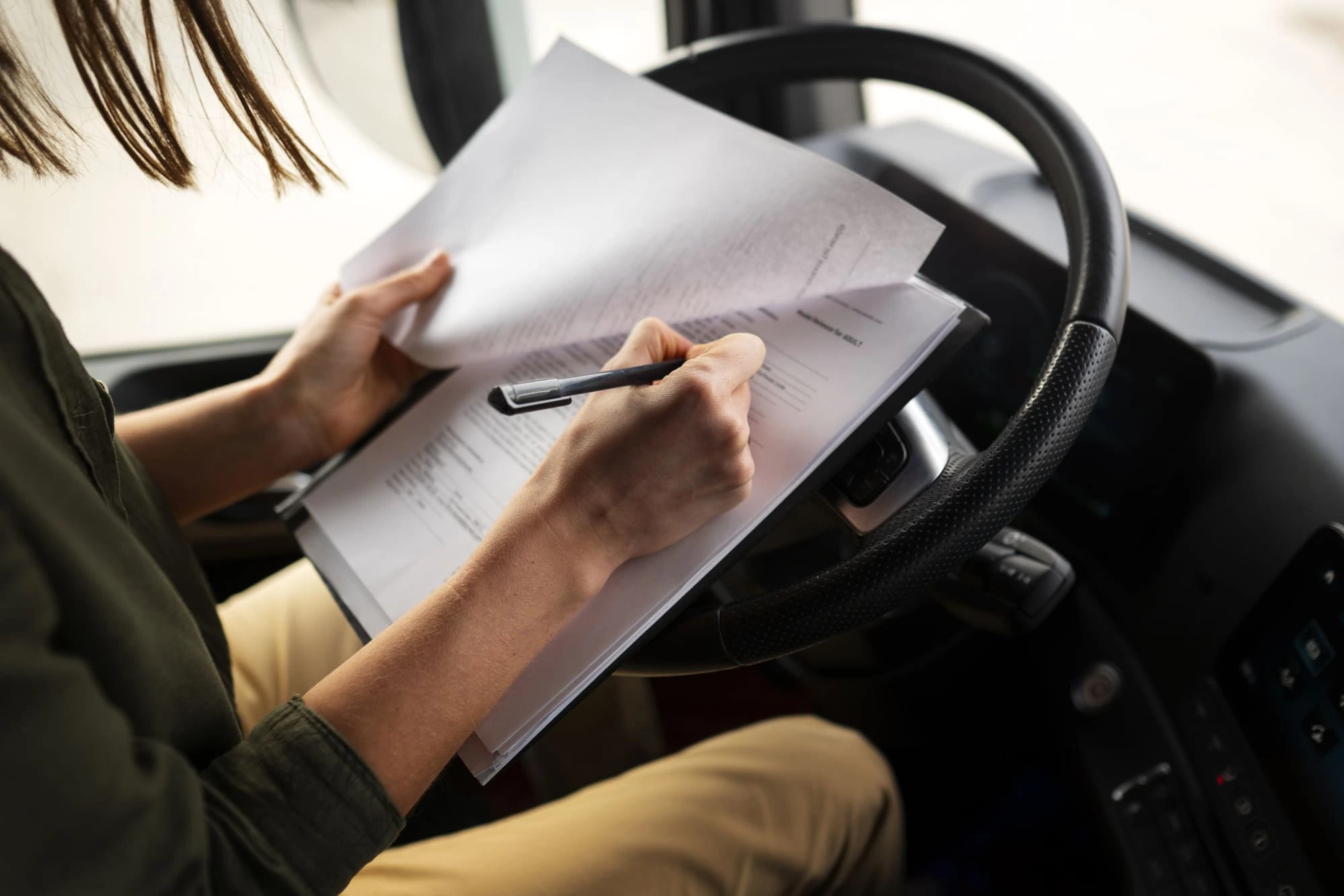 Une personne en train de remplir des papiers dans son camion, au niveau de la place conducteur